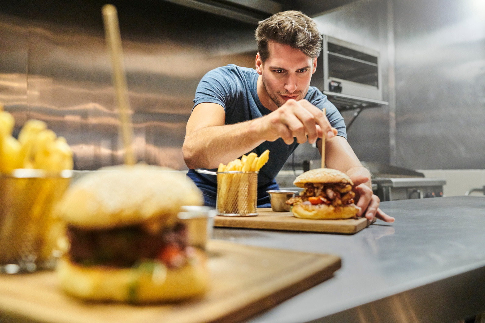 Chef preparing burger on plate at restaurant